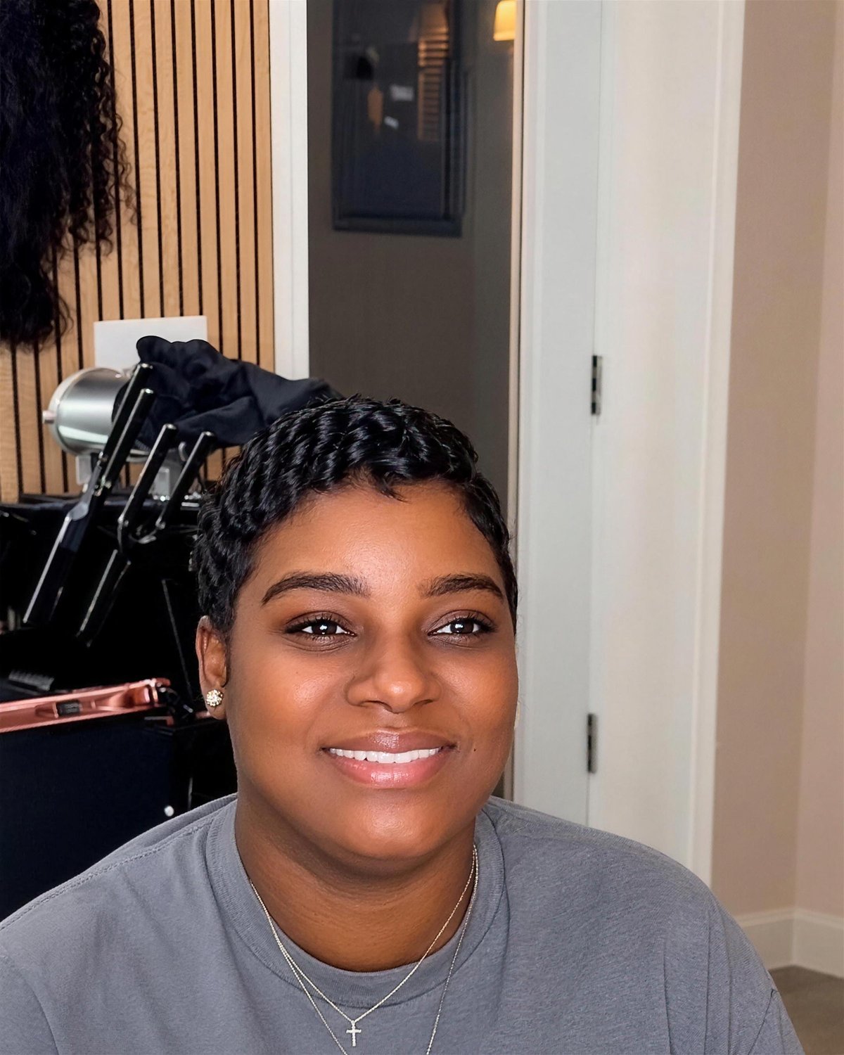 Short pixie cut with soft waves, client smiling in the chair.